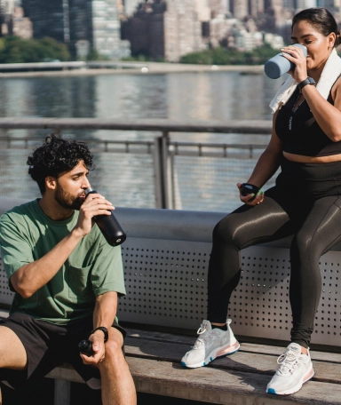 a couple sitting on a bench drinking water